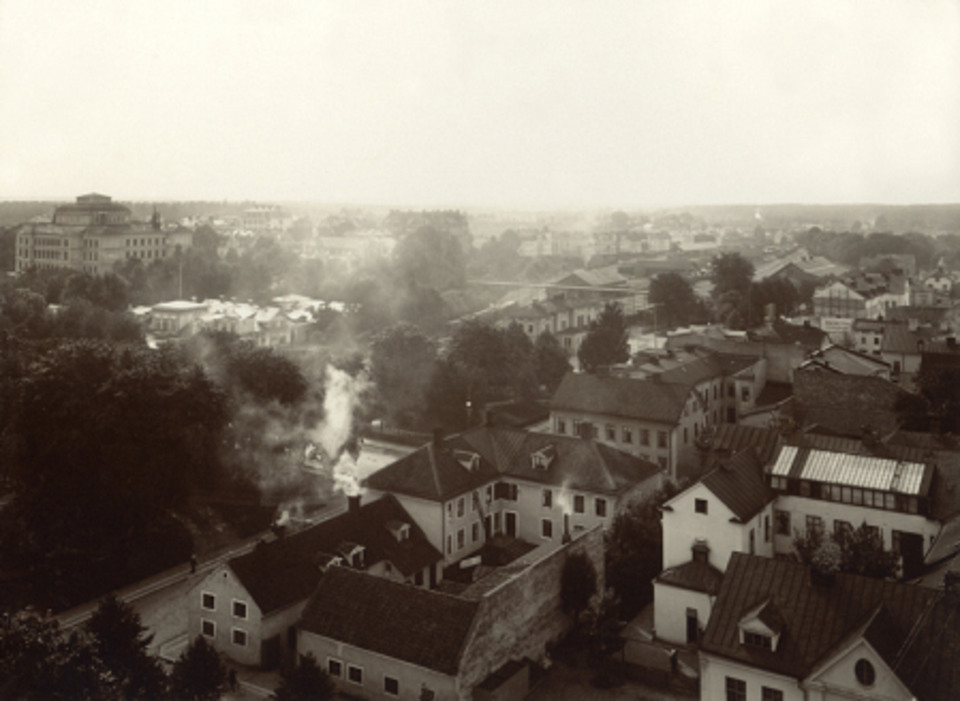 Vy av Norra Järnvägsgatan österut, i korsningen mot Klostergatan. Systembolaget låg länge i det vita huset i förgrunden. Till höger ser du träden längs stationssidan. Fotograf: Betty Larsons eftr. Ivan Persson.