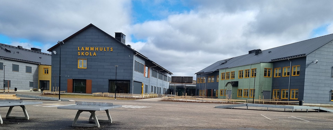 En grå byggnad med asfalt och en lekplats framför.
