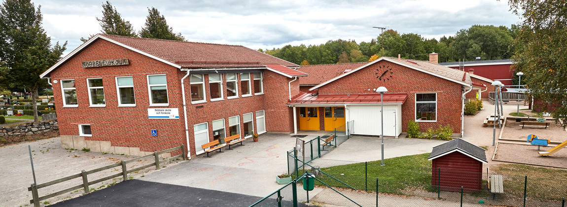 En röd tegelbyggnad. Skolans namn står på fasaden